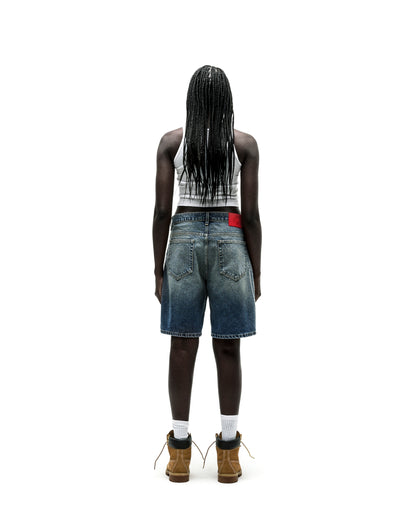 Vintage wash denim shorts with a red leather patch, worn by a person facing away.