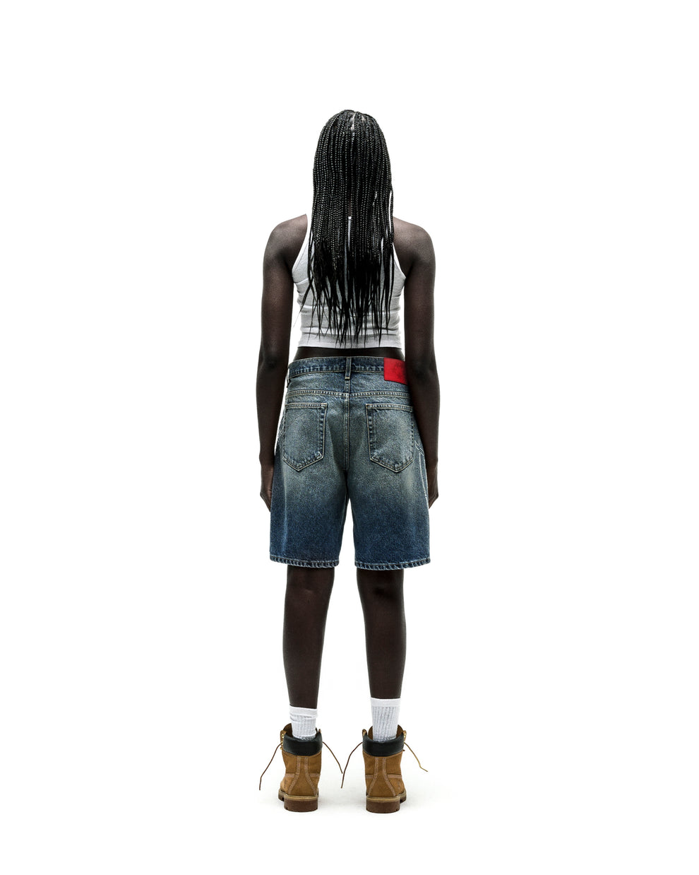 Vintage wash denim shorts with a red leather patch, worn by a person facing away.