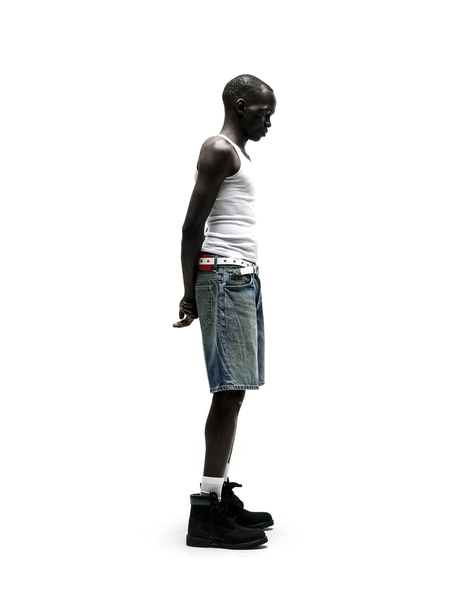 Man in vintage wash denim shorts with belt loops, five-pocket styling, and branded hardware.