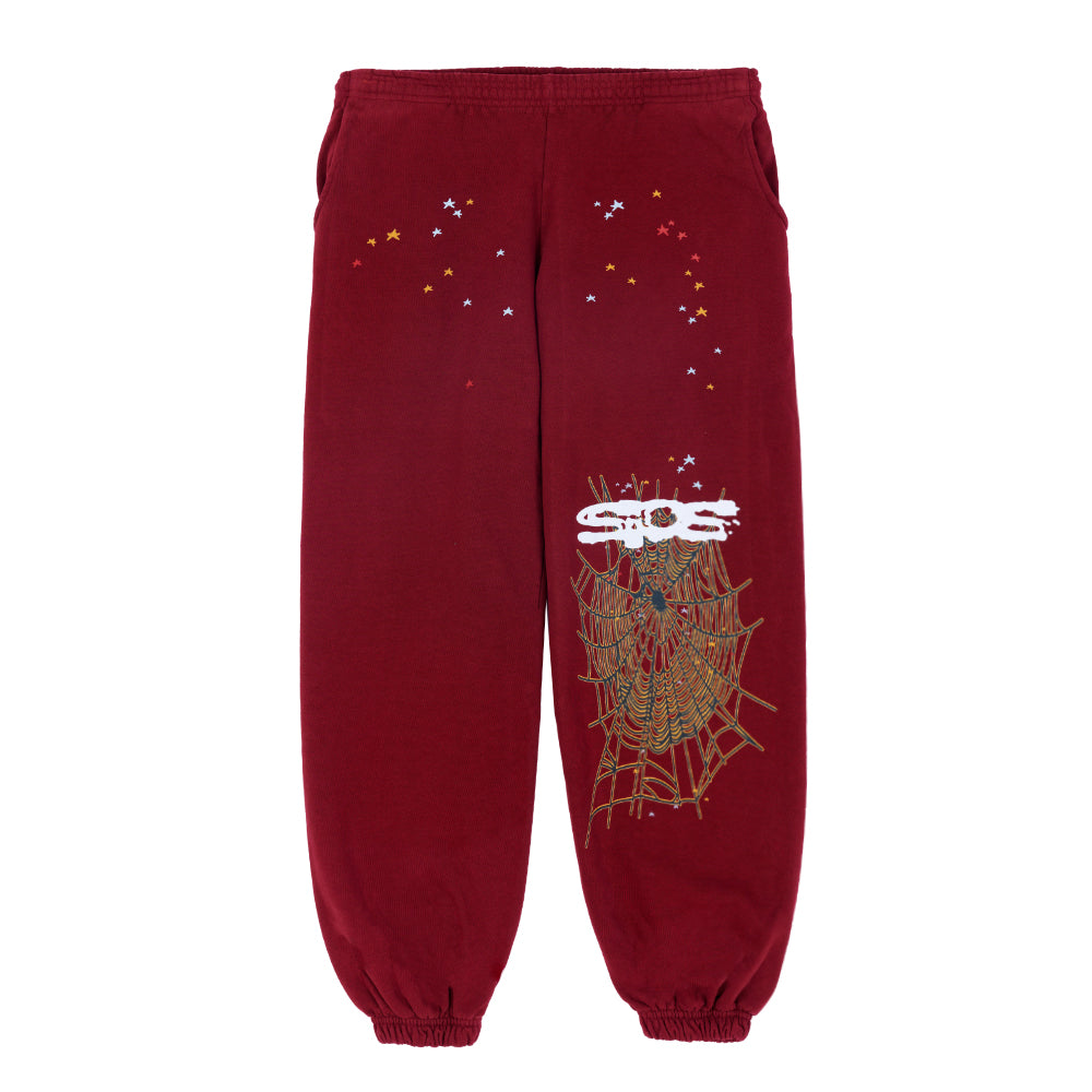 Red SP5DER sweatpants with puff print stars and a large spider web graphic on the leg.