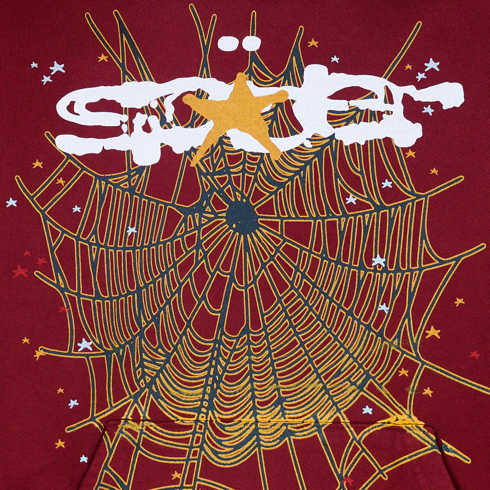 Red SP5DER hoodie with large gold spider web and white puff print logo.