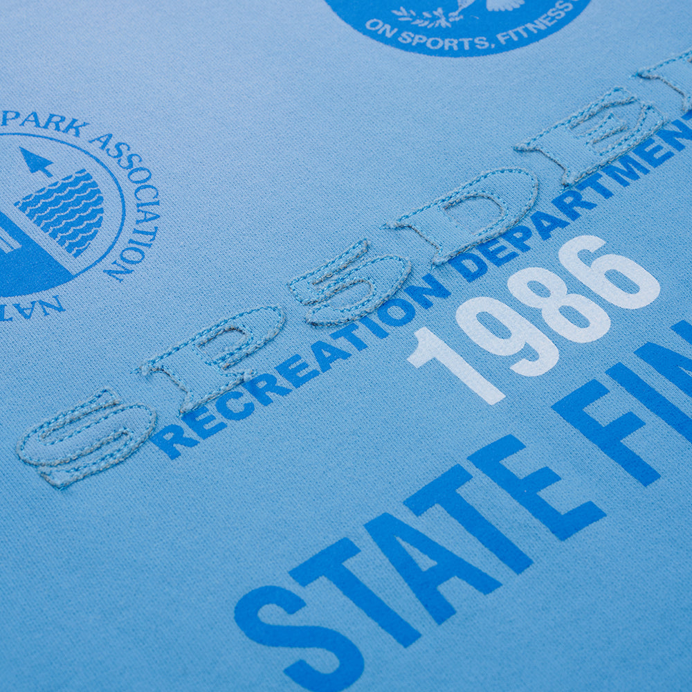 Light blue French terry sweatshirt with "SP5DER" applique, "RECREATION DEPARTMENT 1986" screen print, and "PARK ASSOCIATION" logo.