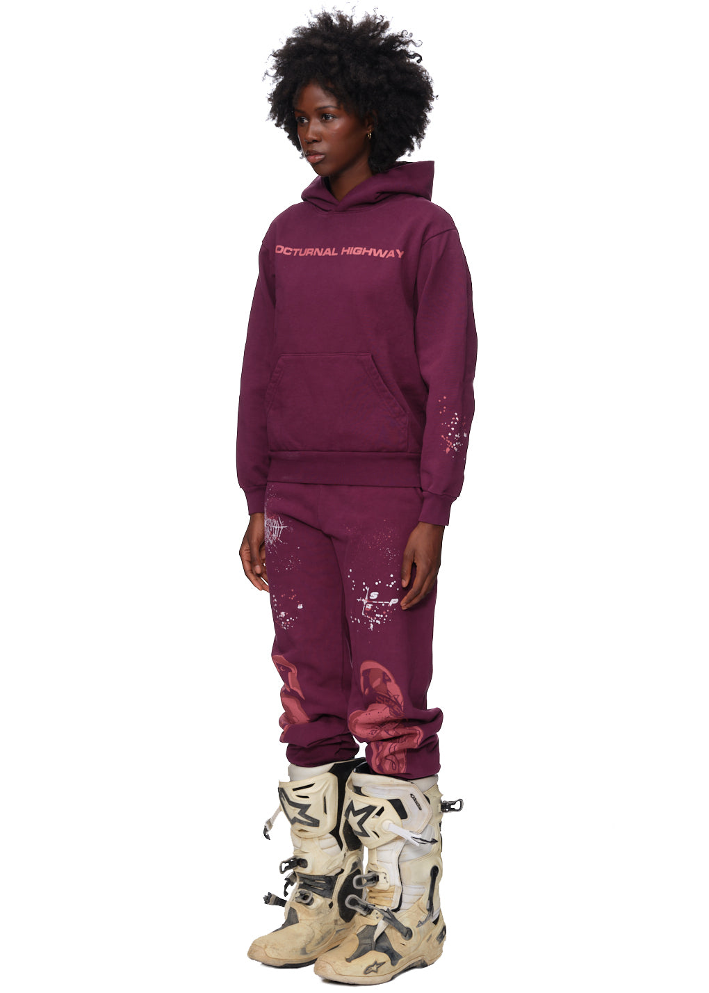 Model wearing a purple 23oz fleece hoodie with "NOCTURNAL HIGHWAY" puff print and matching sweatpants.