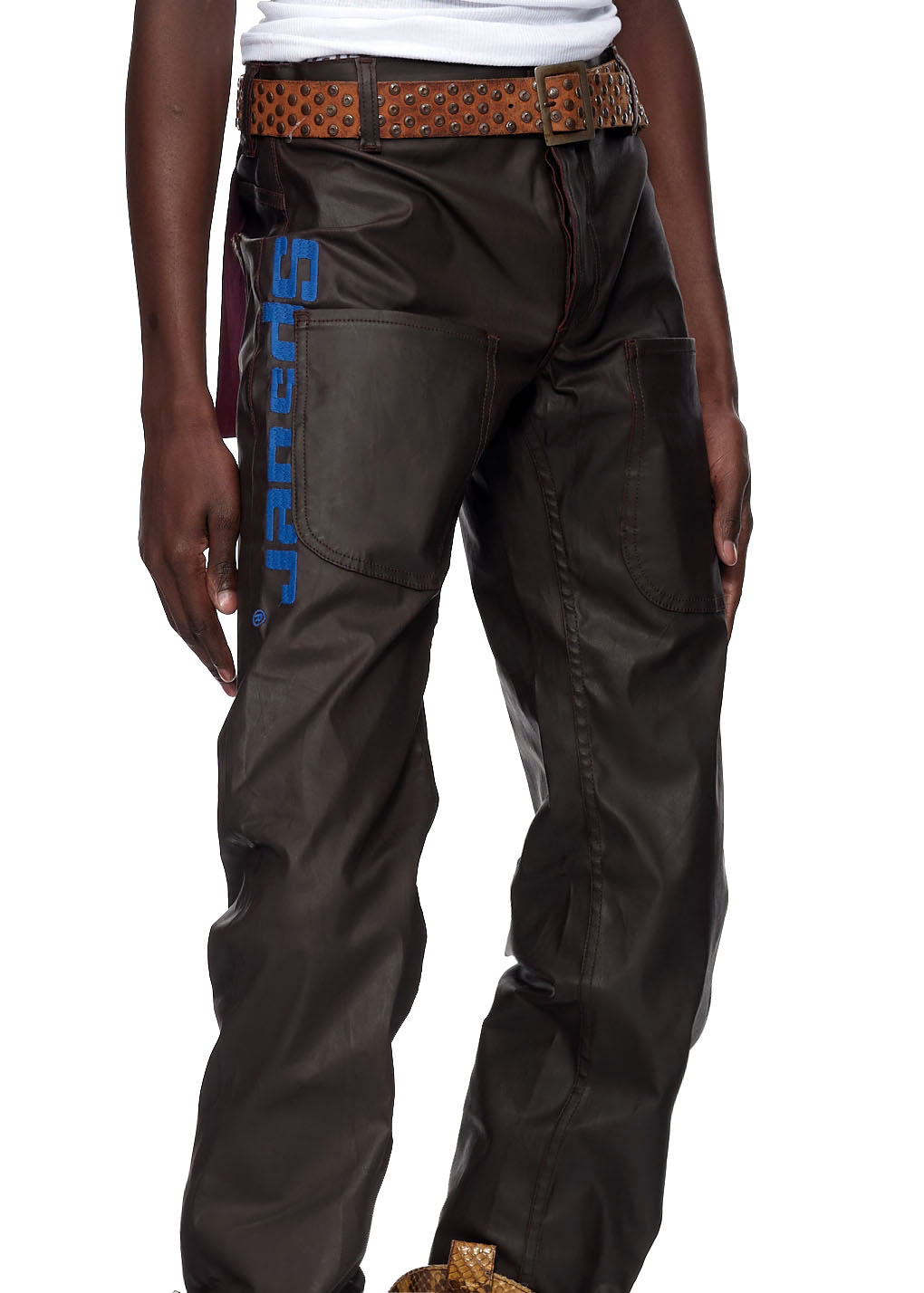 Brown coated canvas SP5DER front pocket jeans with blue embroidered logo and studded belt.