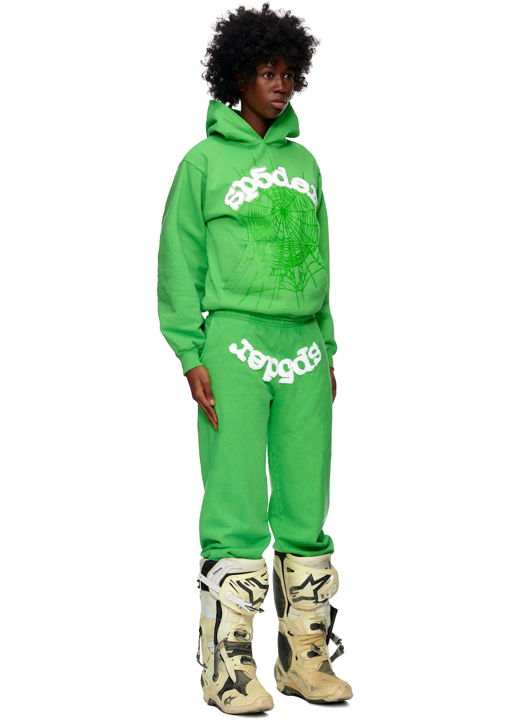 Green SP5DER WEB HOODIE and sweatpants set with white puff print web design, worn by a person.