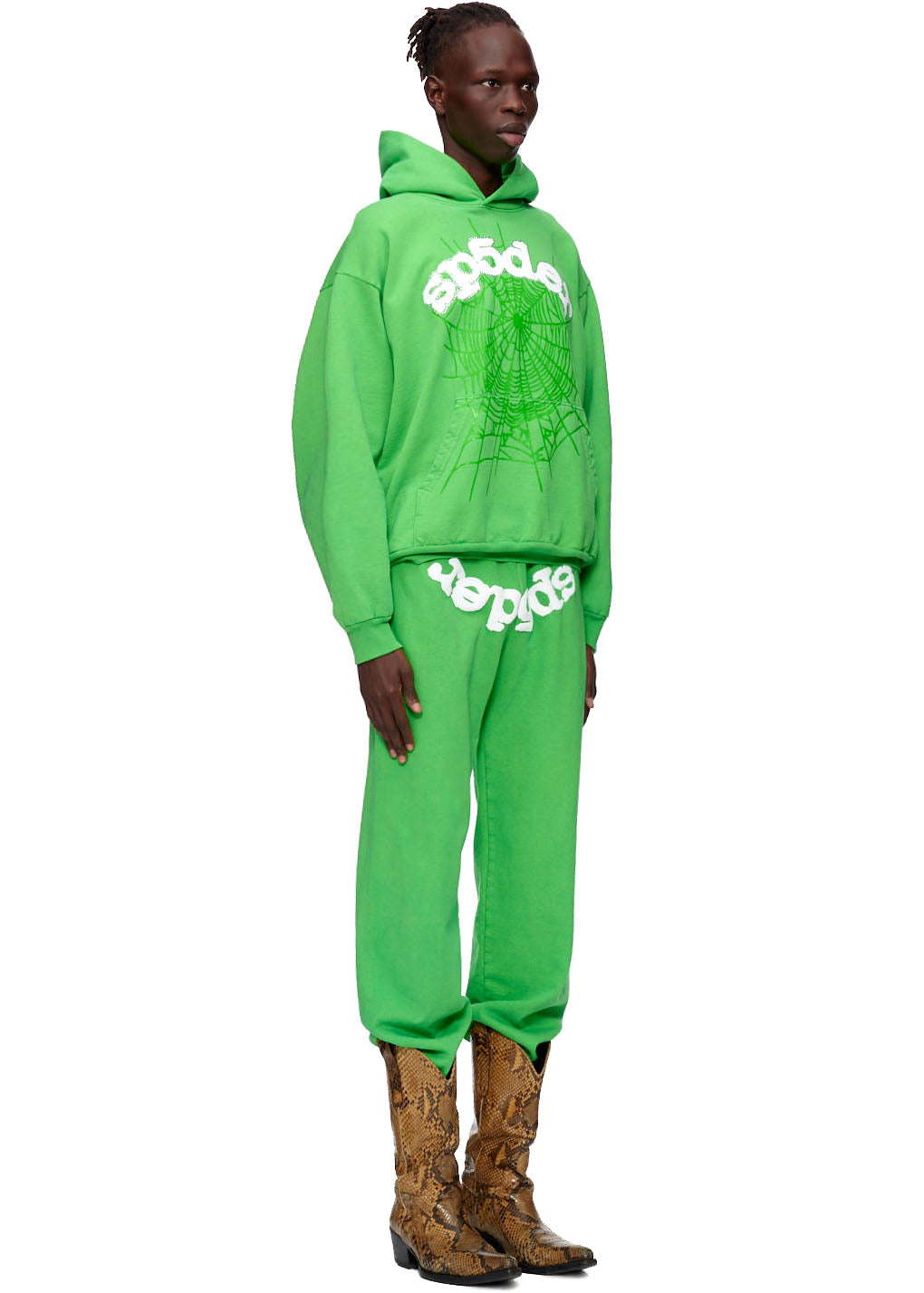 Model wearing a vibrant green SP5DER WEB HOODIE and sweatpants with a white web graphic and text.
