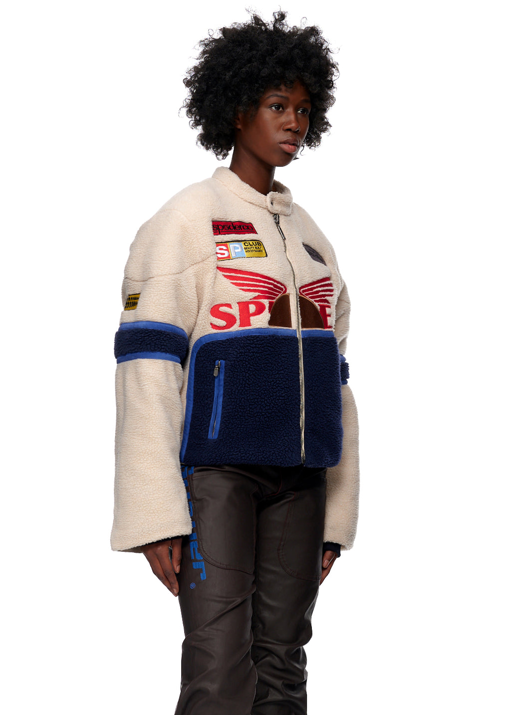 Cream sherpa cafe racer jacket with navy accents, leather trim, and SP5DER patches.