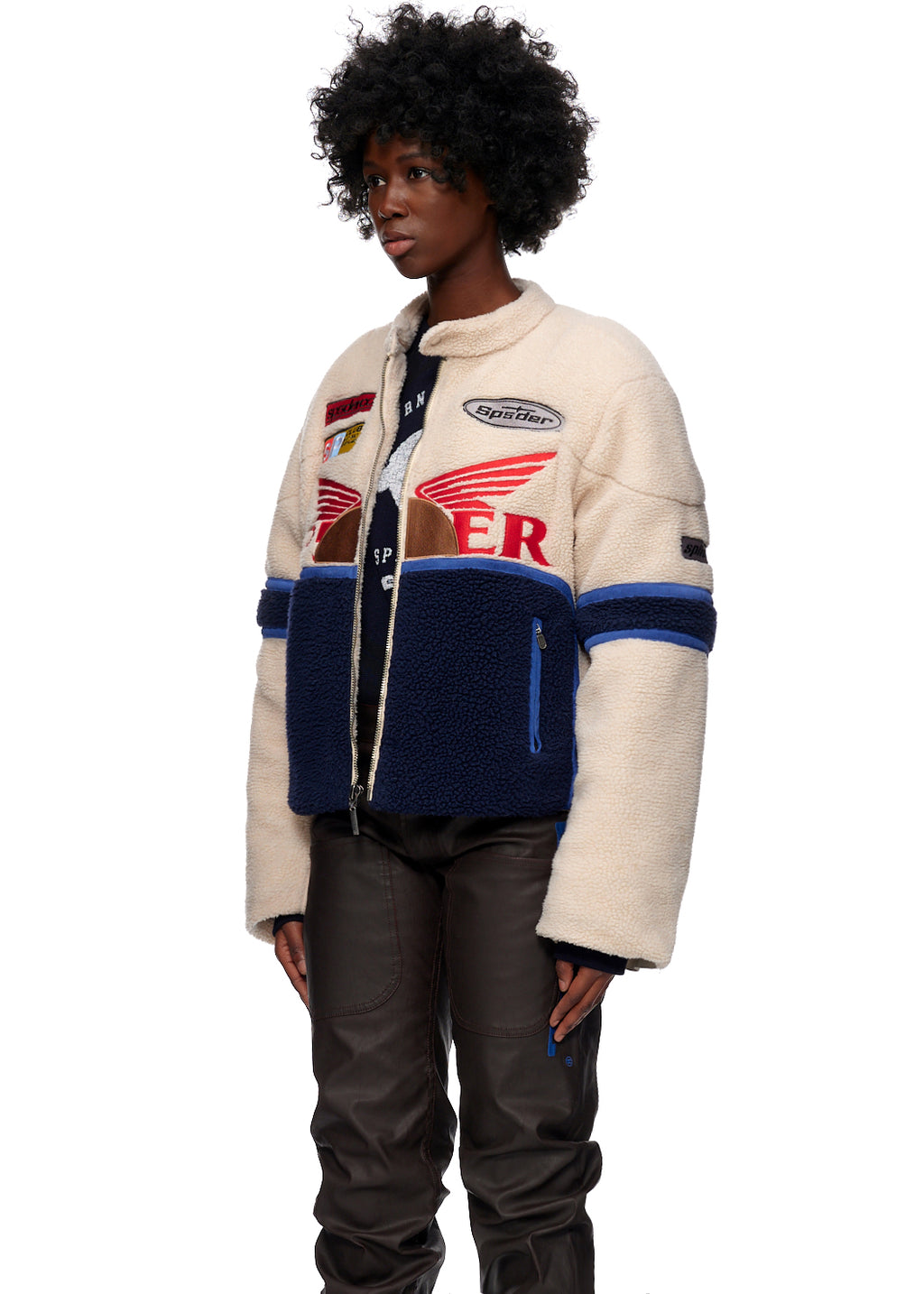 Sherpa Cafe Racer jacket: cream and navy fleece with leather trim, SP5DER patches, and blue stripes.