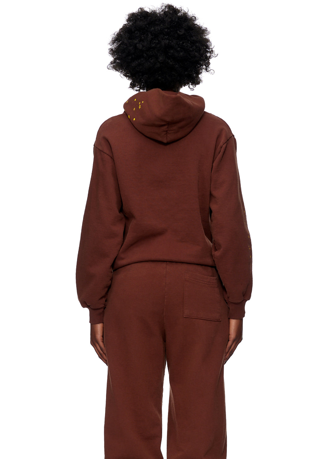 Back view of a person wearing a brown WEB HOODIE and matching sweatpants, featuring yellow SP5DER web print.