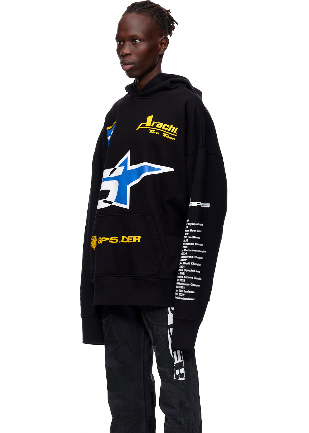 Black oversized hoodie with yellow and blue graphics, "Arachi Re-Tech" logo, and "SP5.DER" on pocket.