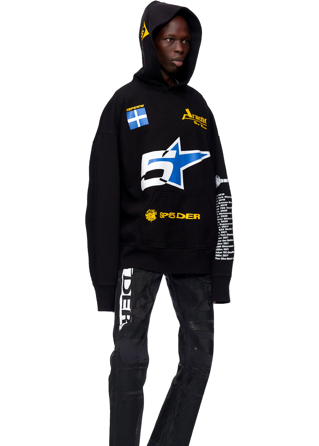 Black oversized hoodie with yellow, blue, and white graphics, worn by a model.