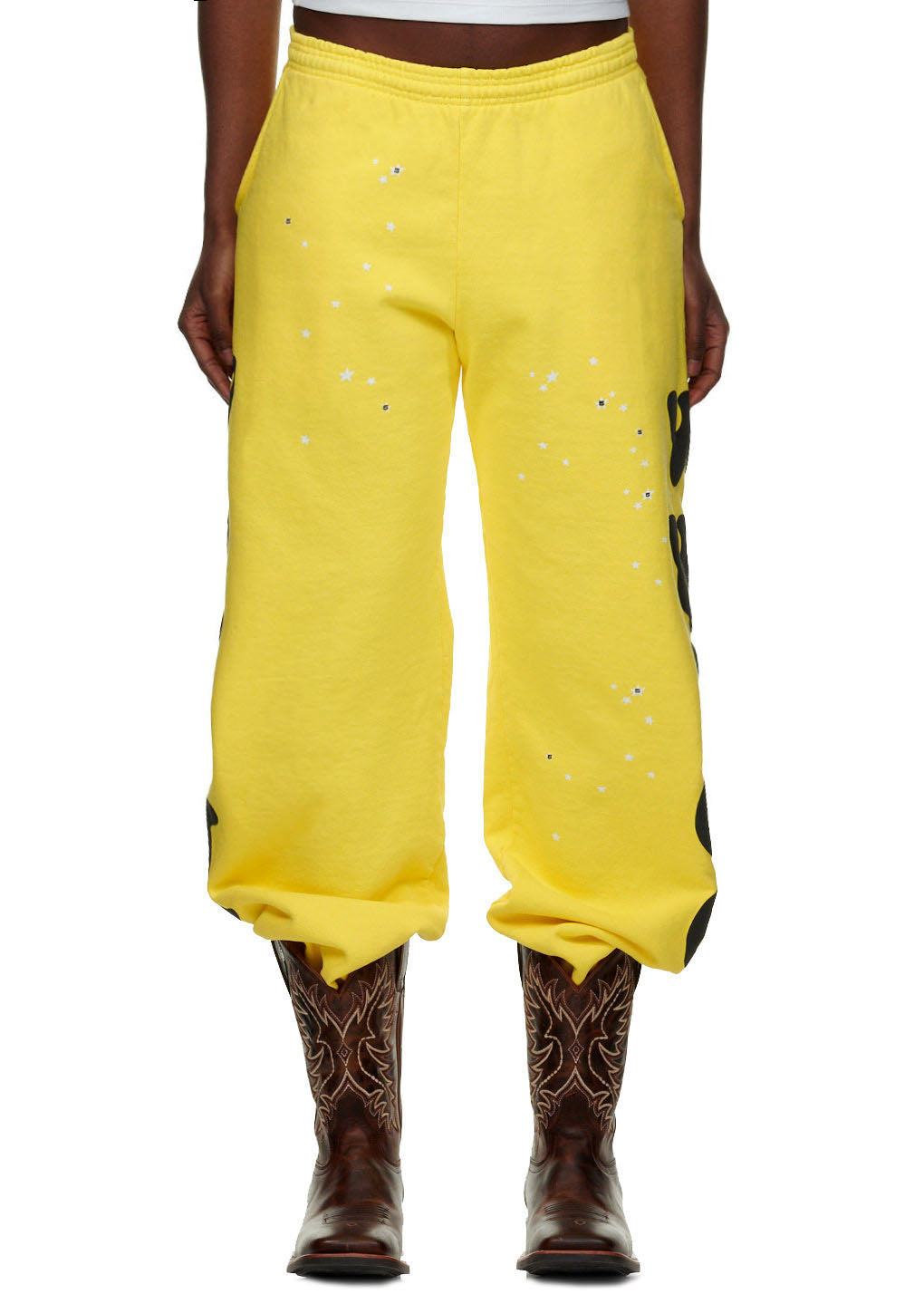 Yellow BELUGA SWEATPANT with white stars and black 'Worldwide' puff print, worn with cowboy boots.