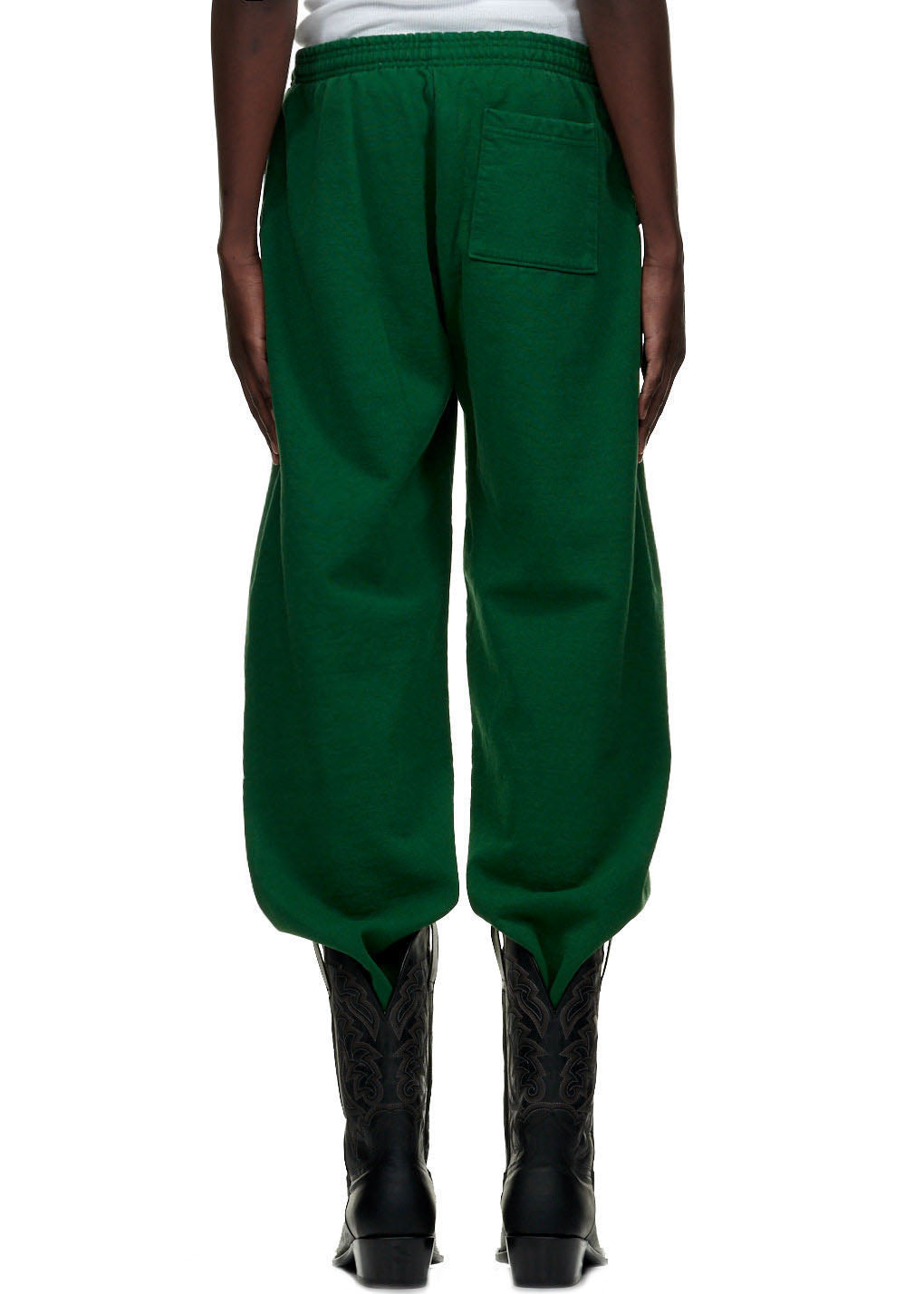 Back view of green 23oz fleece WEB SWEATPANT with SP5DER web print on left leg, worn with black cowboy boots.