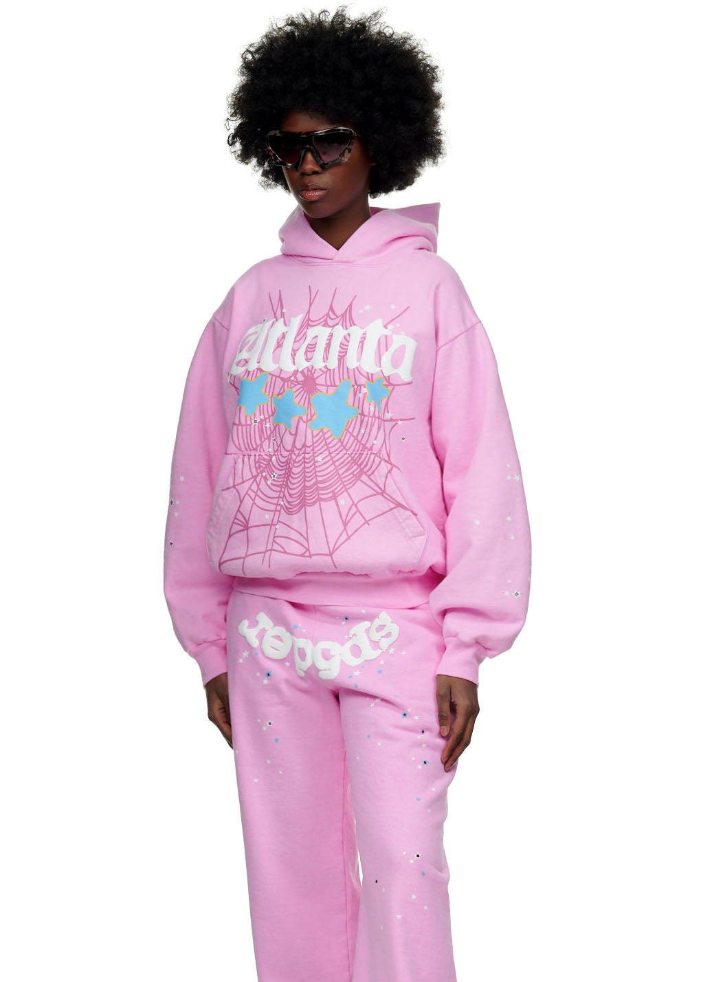 Female model in an oversized pink Atlanta hoodie and matching sweatpants with spiderweb and star prints.